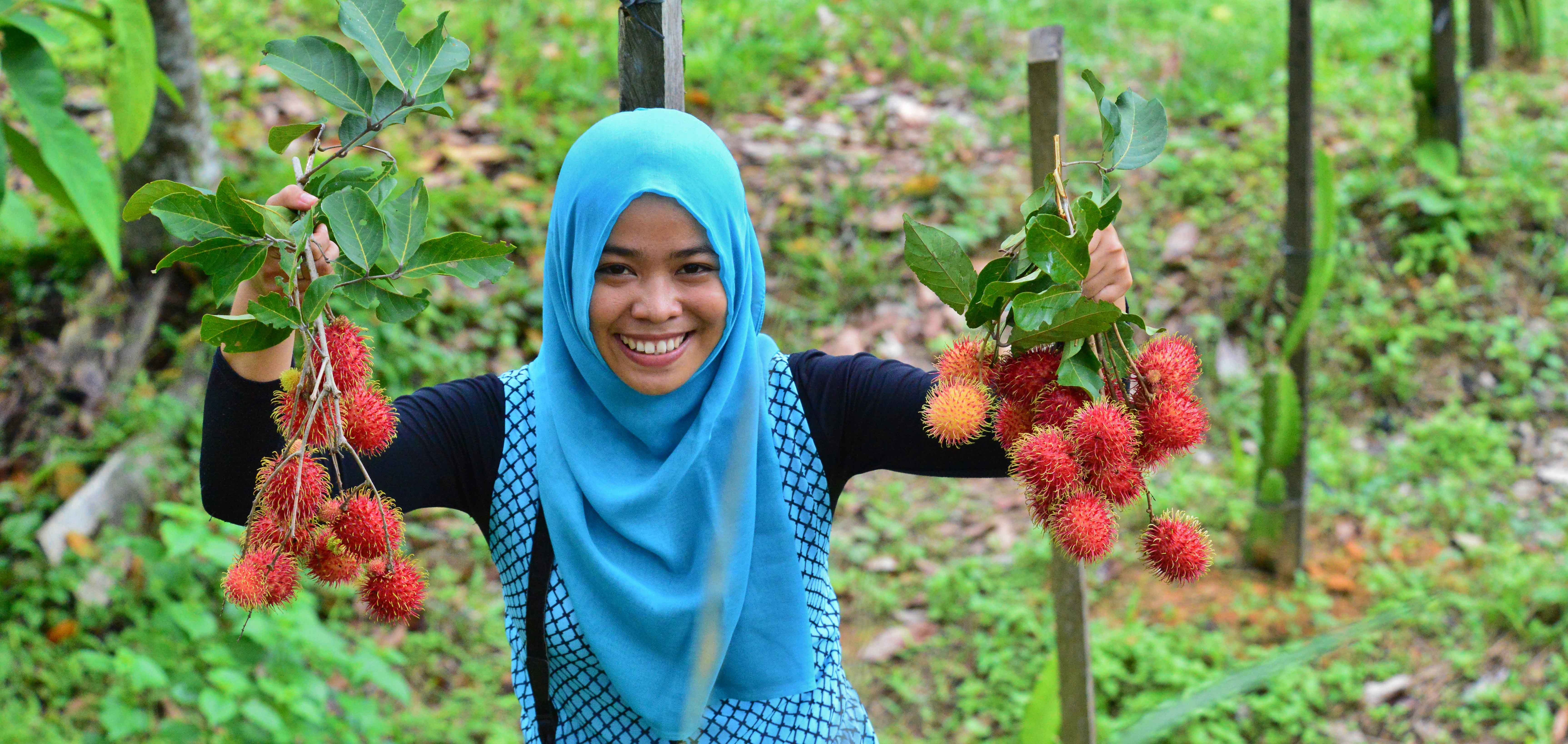 Woman holding rambutan, a redish orange fruit